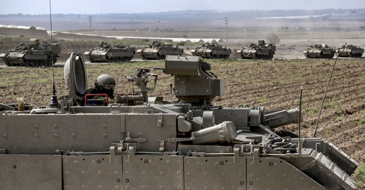 An Israeli army soldier sits in the hatch of a Puma armoured personnel carrier (APC) in a column with other vehicles near the Gaza border in southern Israel. Photo: AFP