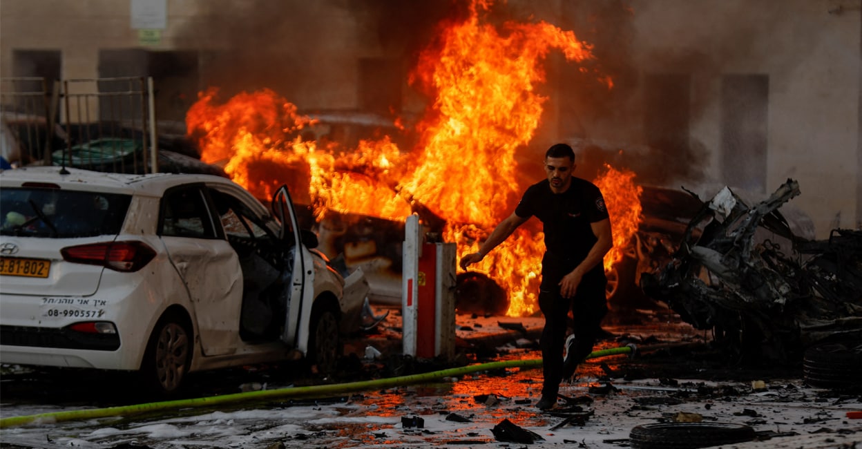 hamas-attack-add-2 A man runs on a road as fire burns after rockets were launched from the Gaza Strip, in Ashkelon, Israel, on Saturday. Photo: REUTERS/Amir Cohen