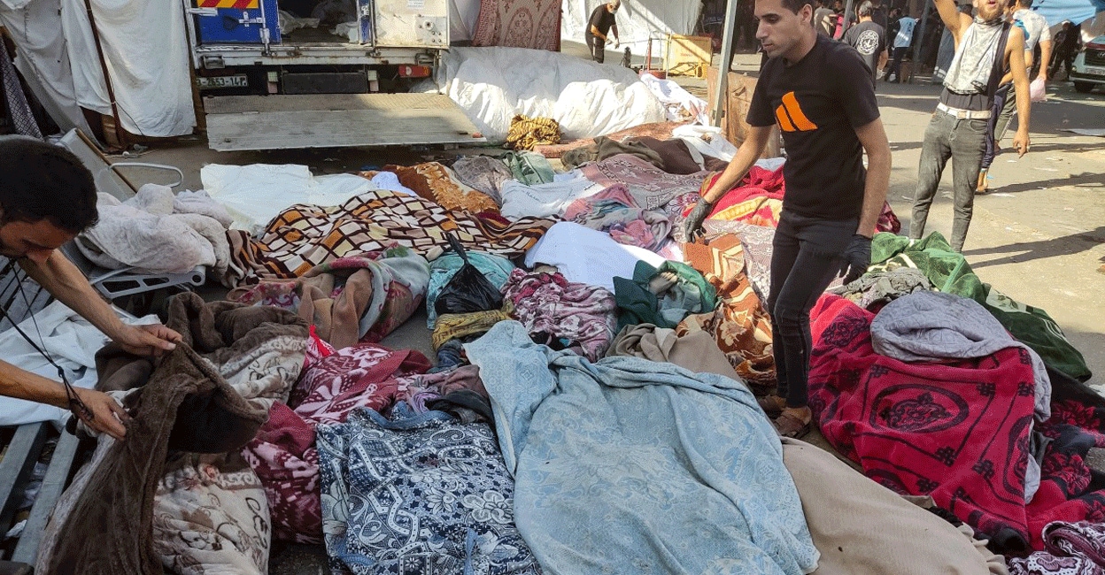 PALESTINIAN-ISRAEL-CONFLICT Men check the bodies of people killed in bombardment that hit a school housing displaced Palestinians, as they lie on the ground in the yard of Al-Shifa hospital in Gaza City on November 10, 2023, amid ongoing battles between Israel and the Palestinian Hamas movement. About 50 bodies were recovered on November 10 after a Gaza City school was hit by strikes, said the director of Al-Shifa hospital where the casualties had been taken. Photo: AFP/ Khoder al-Zaanoun