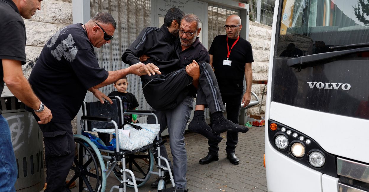 israel-hamas-battle-2 A man carries a patient as other patients from Gaza who have been receiving treatment at Makassed Hospital wait to be transported by bus to the Israeli-occupied West Bank, after they were refused permission to stay, in East Jerusalem on November 13, 2023. Photo: Reuters/James Oatway