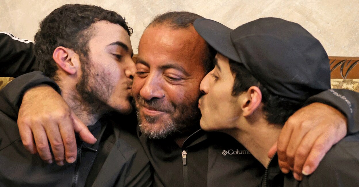 PALESTINIAN-ISRAEL-CONFLICT-PRISONERS Palestinian brothers Qassam (left) and Nasrallah (right) reunite with their father Iyad Al-Awar after both were released from an Israeli prison as part of an hostage deal between Israel and Hamas, at their home in Israeli-annexed east Jerusalem on November 26, 2023. Photo: AFP/ Ahmad Gharabli