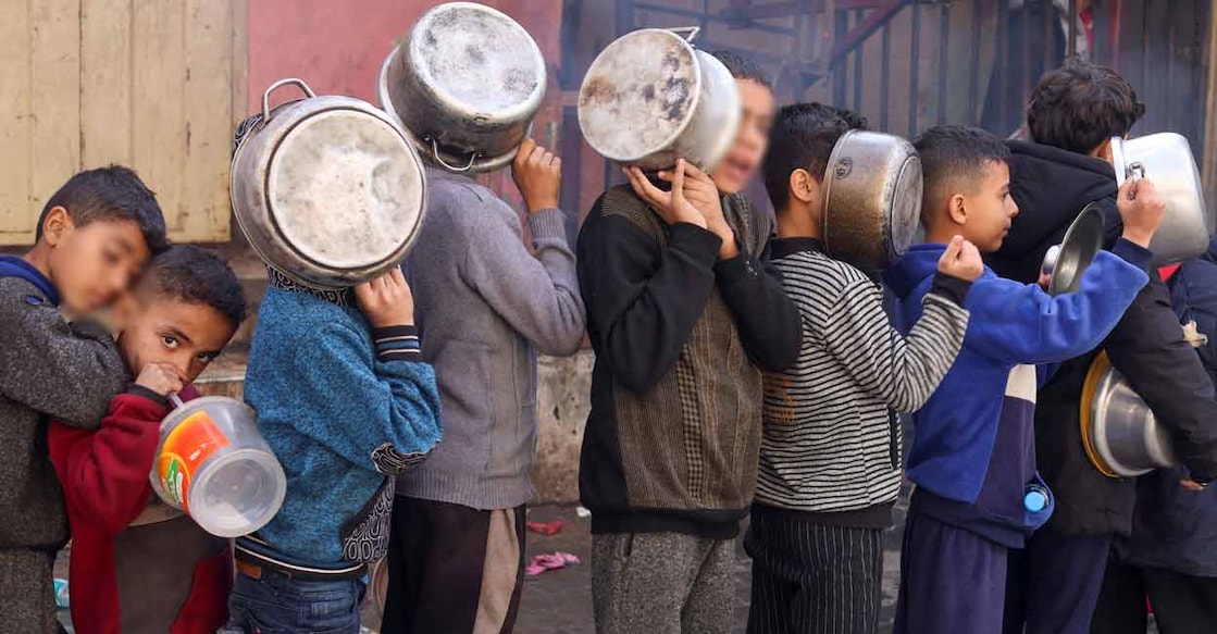 Palestinian children carry pots as they queue to receive food cooked by a charity kitchen, amid shortages in food supplies, as the conflict between Israel and Hamas continues, in Rafah in the southern Gaza Strip December 14, 2023. File photo: REUTERS/Saleh Salem
