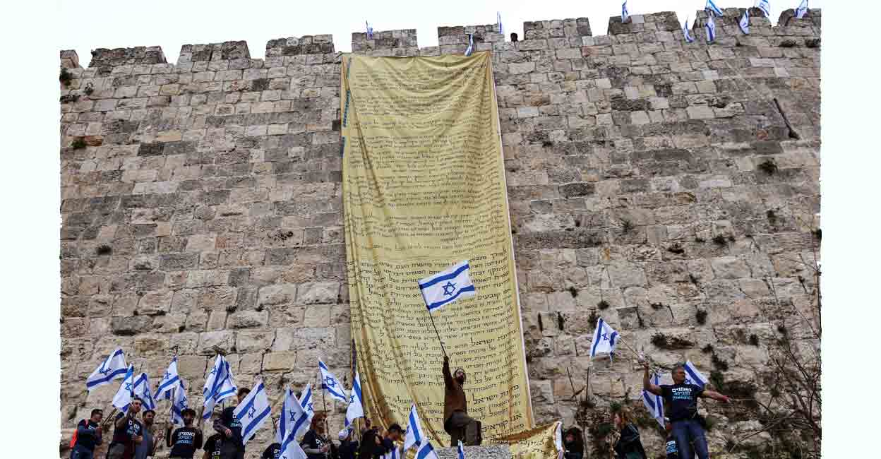 Israel protest Demonstrators wave flags after hanging copies of the Israeli Declaration of Independence on the walls of Jerusalem's Old City in an act of protest as Israeli Prime Minister Benjamin Netanyahu's nationalist coalition government presses on with its contentious judicial overhaul, in Jerusalem, March 23, 2023. Photo: REUTERS/Ronen Zvulun