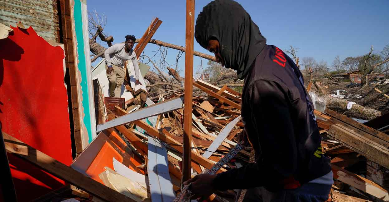 The son and nephew of Cedric Miles search for belongings inside the Miles family home after thunderstorms spawning high straight-line winds and tornadoes ripped across the state in Rolling Fork, Mississippi, U.S. March 25, 2023. Photo: Reuters/Cheney Orr