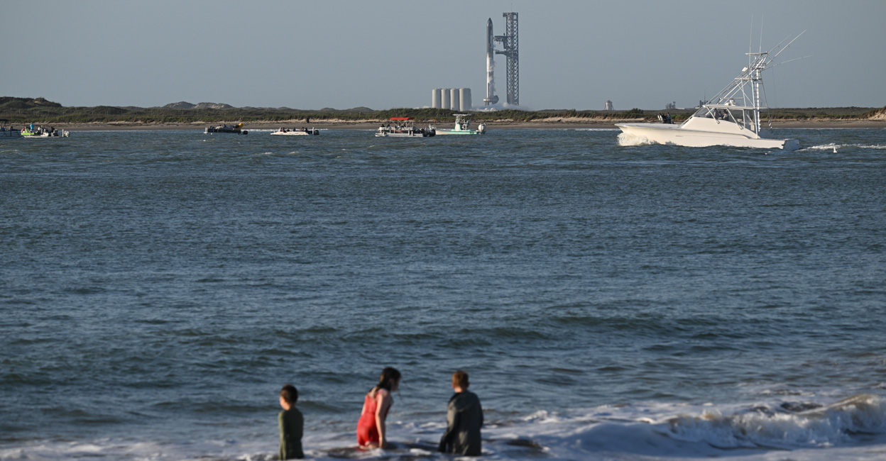 US-SPACE-AEROSPACE-SPACEX-STARSHIP Kids play in the water in South Padre Island, Texas on Monday with the SpaceX Starship rocket standing on the launchpad in the background. Photo: AFP/Patrick T. Fallon