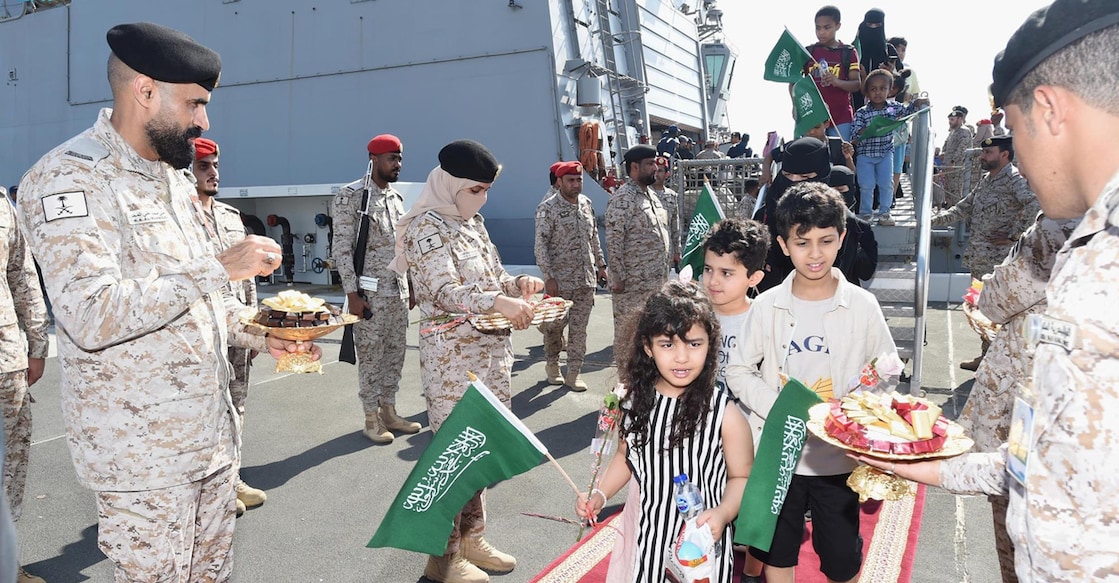 A handout picture provided by the Saudi Press Agency (SPA) on April 22, 2023, shows members of the armed forces passing out chocolates and flowers to Saudi citizens and other nationals upon their arrival in Jeddah, following their rescue from Sudan. Credit: AFP