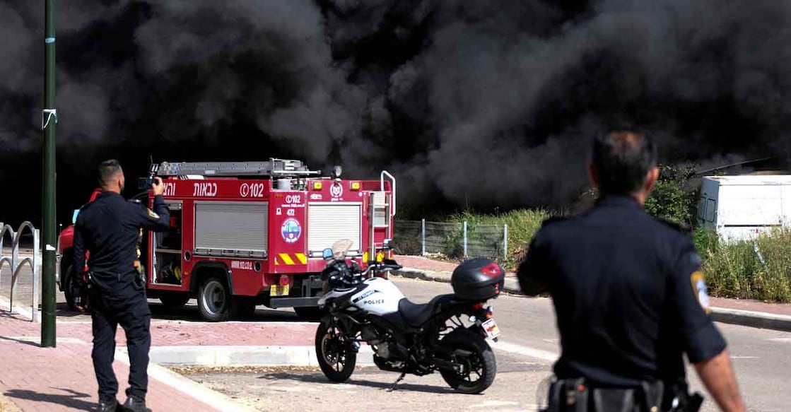 Israeli policemen stand next to smoke from a fire following incoming rockets from Lebanon to Israel in Bezet, northern Israel, April 6, 2023. Photo: Reuters/Fadi Amun
