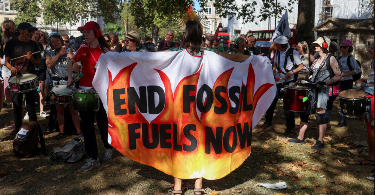 A demonstrator is draped in a piece of fabric with a slogan as activists take part in a global protest to end fossil fuels, in London, Britain, September 16. Photo: Reuters /Susannah Ireland