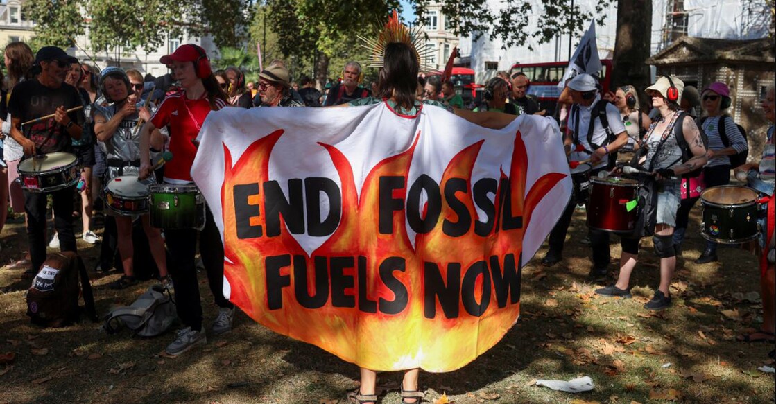 A demonstrator is draped in a piece of fabric with a slogan as activists take part in a global protest to end fossil fuels, in London, Britain, September 16. Photo: Reuters /Susannah Ireland