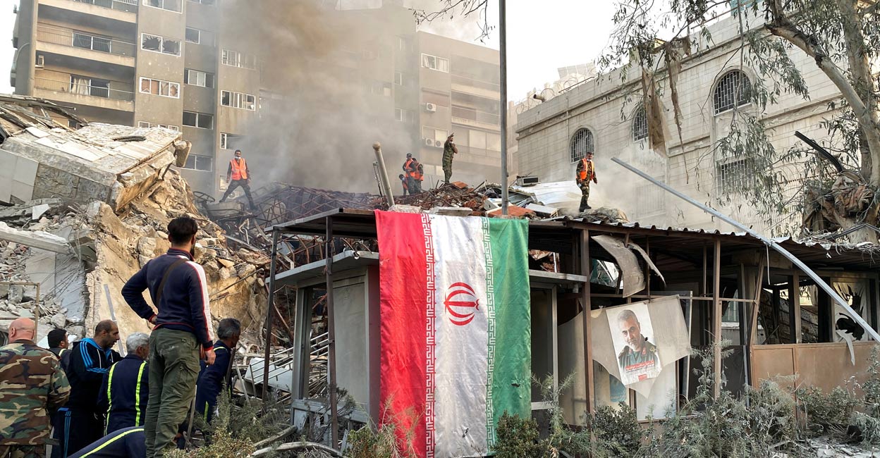iran-syria-bombing1-ls An Iranian flag hangs as smoke rises after what the Iranian media said was an Israeli strike on a building close to the Iranian embassy in Damascus, Syria. Photo: Reuters.