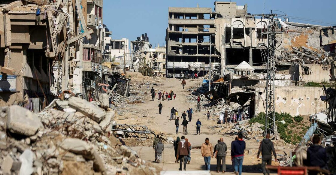 Palestinians walk past the ruins of houses destroyed during Israel's military attack on March 20, 2024. File photo: Reuters/Dawoud Abu Alkas