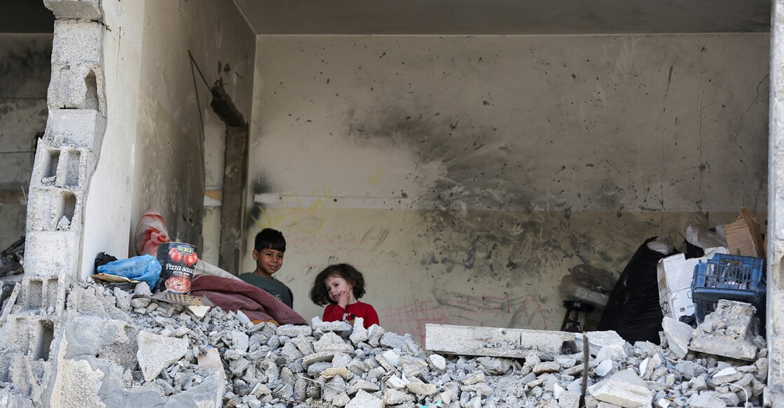 Palestinian kids stand in a house destroyed by an Israeli strike. Photo: Hatem Khaled/Reuters.