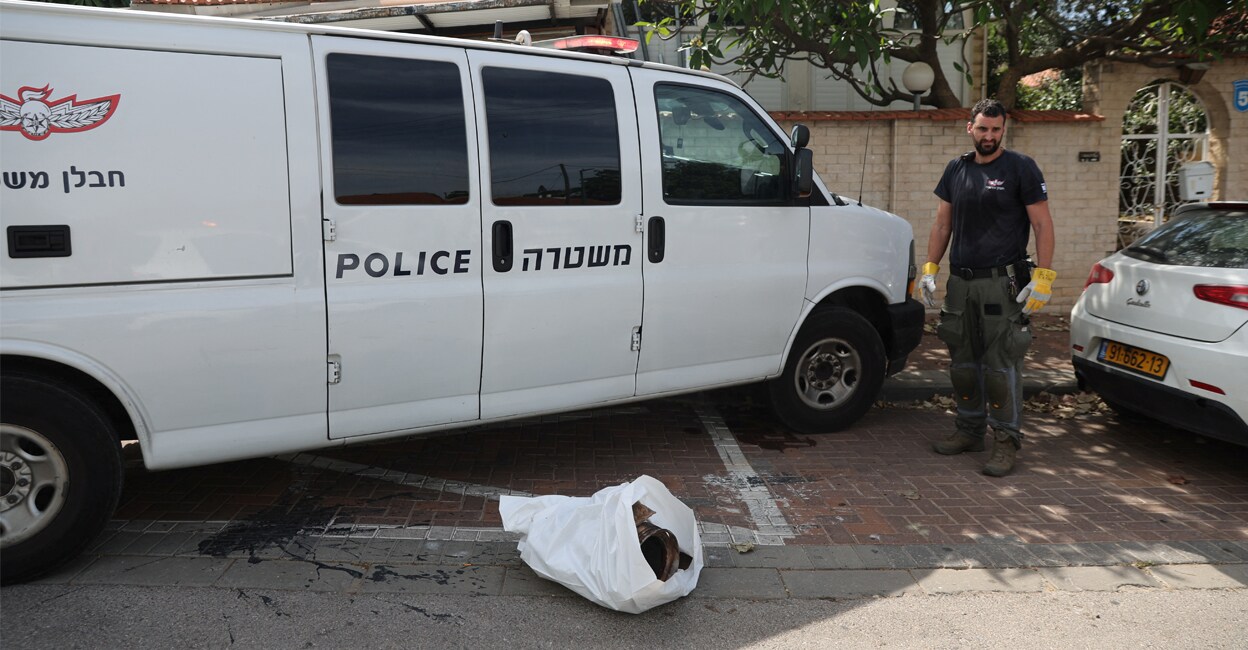 An Israeli police officer stands next to the remains of a rocket after rockets were fired from the Gaza Strip towards Israel. REUTERS/Nir Elias.