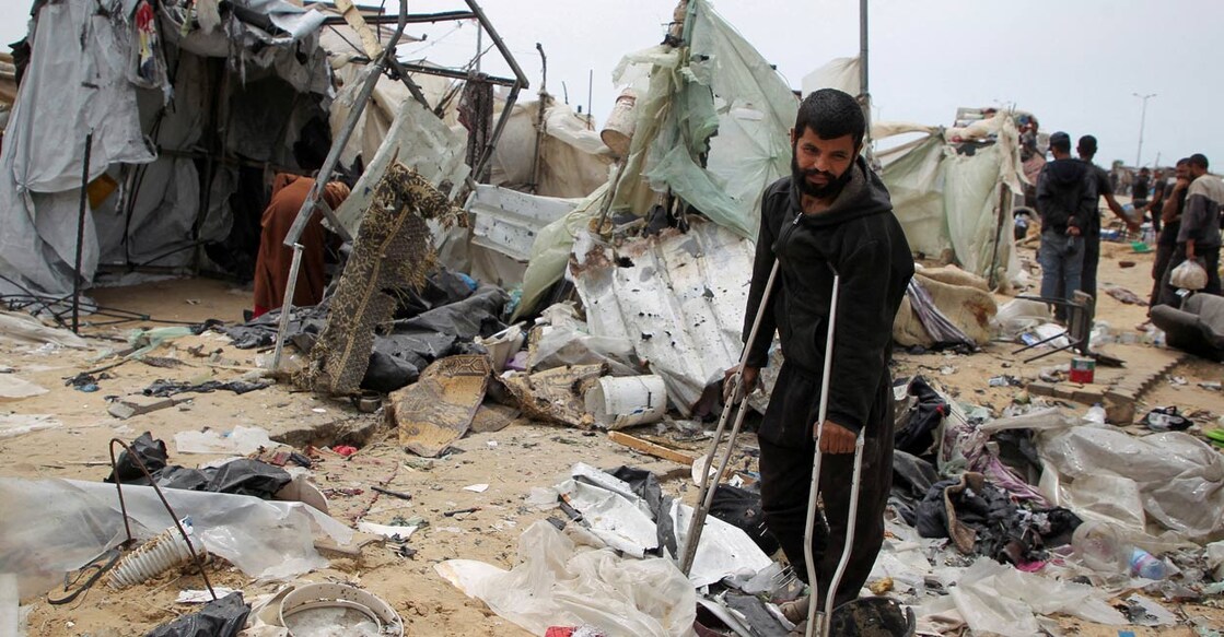 A man looks on as Palestinians inspect a tent camp damaged in an Israeli strike during an Israeli military operation, in Rafah, in the southern Gaza Strip, May 28, 2024. Photo: Reuters. 