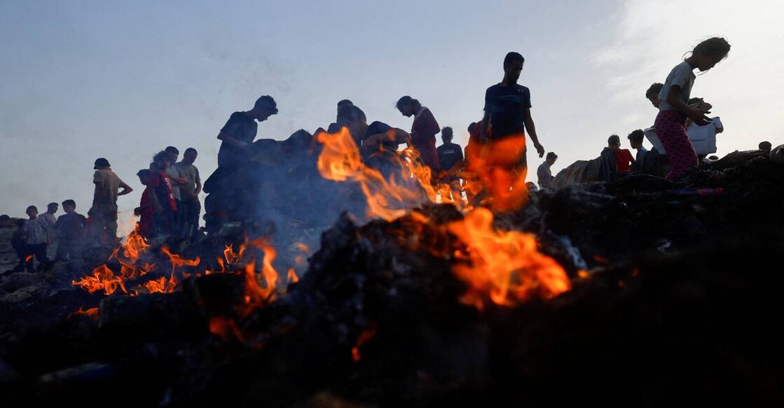 Palestinians search for food among burnt debris in the aftermath of an Israeli strike on an area designated for displaced people, in Rafah. Photo: Reuters