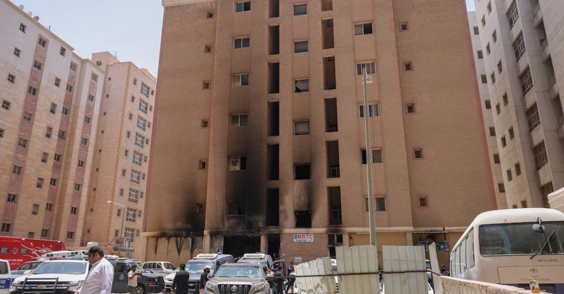 People walk past a building that was engulfed by fire, in Kuwait City. Photo: AFP
