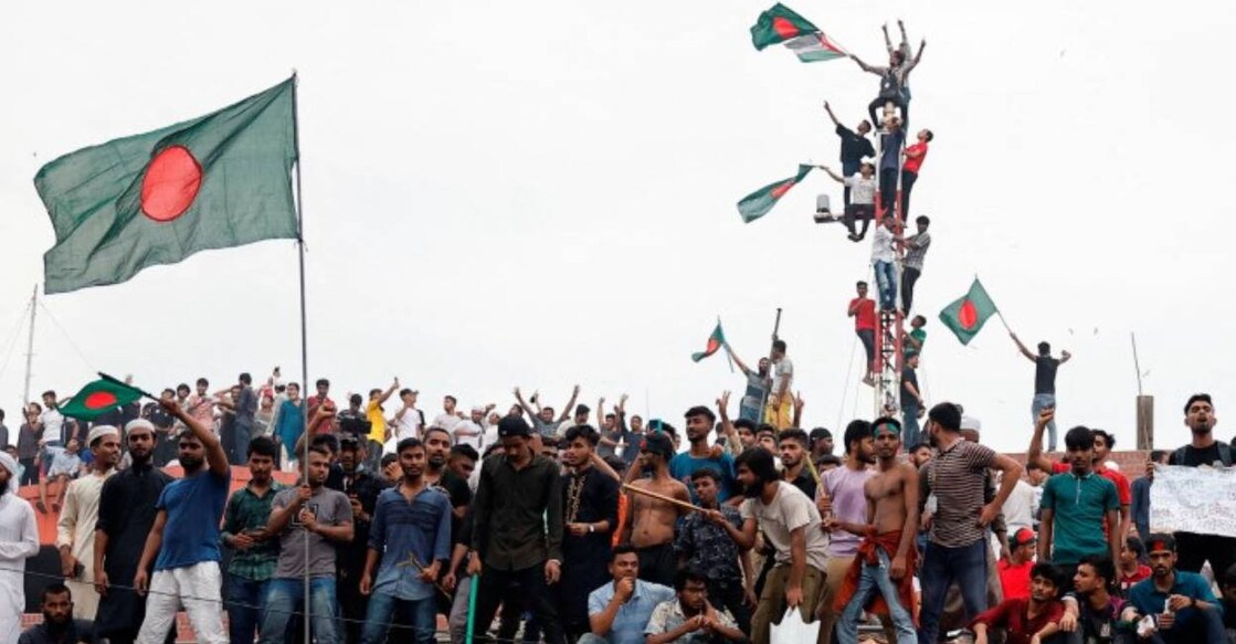 People waves Bangladeshi flags on top the Ganabhaban, the Prime Minister's residence, as they celebrate the resignation of PM Sheikh Hasina in Dhaka. Photo: Reuters