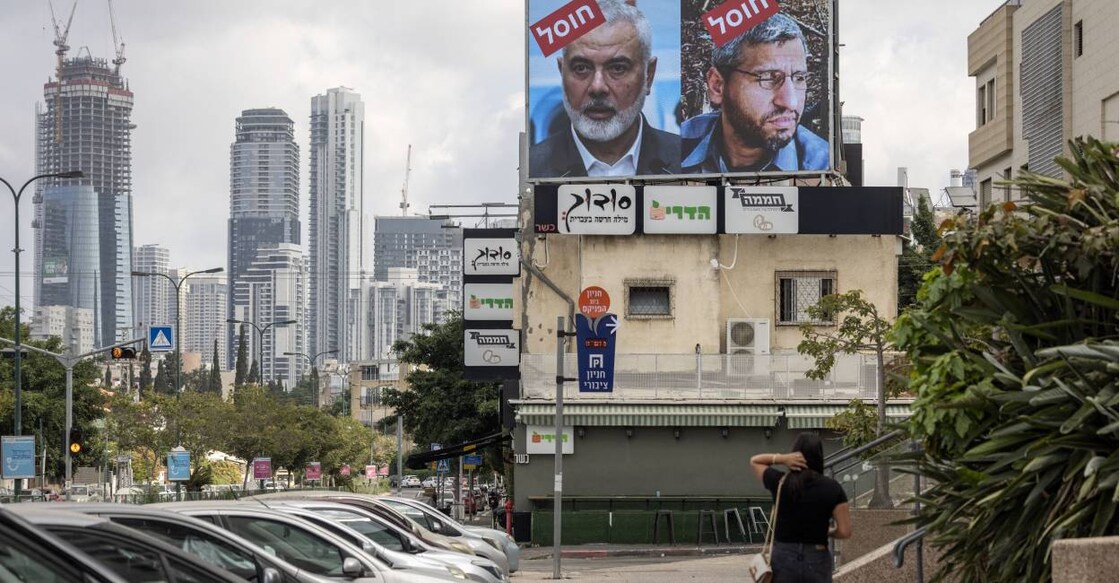 tel-aviv-hamas-leaders-killing A woman walks near a billboard displaying portraits of Hamas leader Mohammed Deif (R) and Ismail Haniyeh with the slogan “assassinated” reading in Hebrew, in Tel Aviv. Photo: AFP