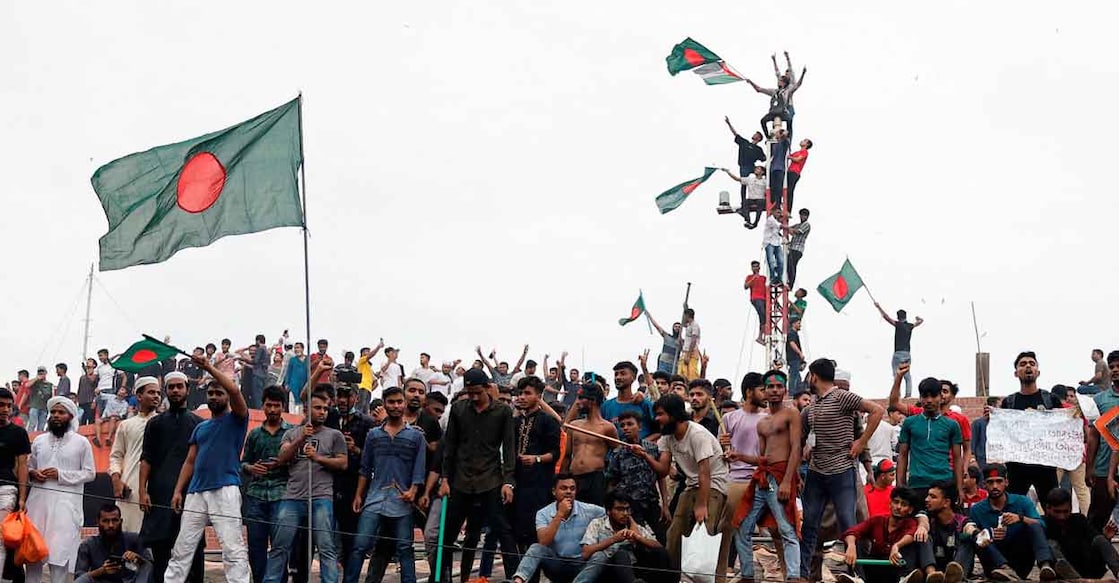 BANGLADESH-PROTESTS/ People wave Bangladeshi flags on top the Ganabhaban, the Prime Minister's residence, as they celebrate the resignation of PM Sheikh Hasina in Dhaka, Bangladesh, August 5, 2024. Photo: Reuters/Mohammad Ponir Hossain