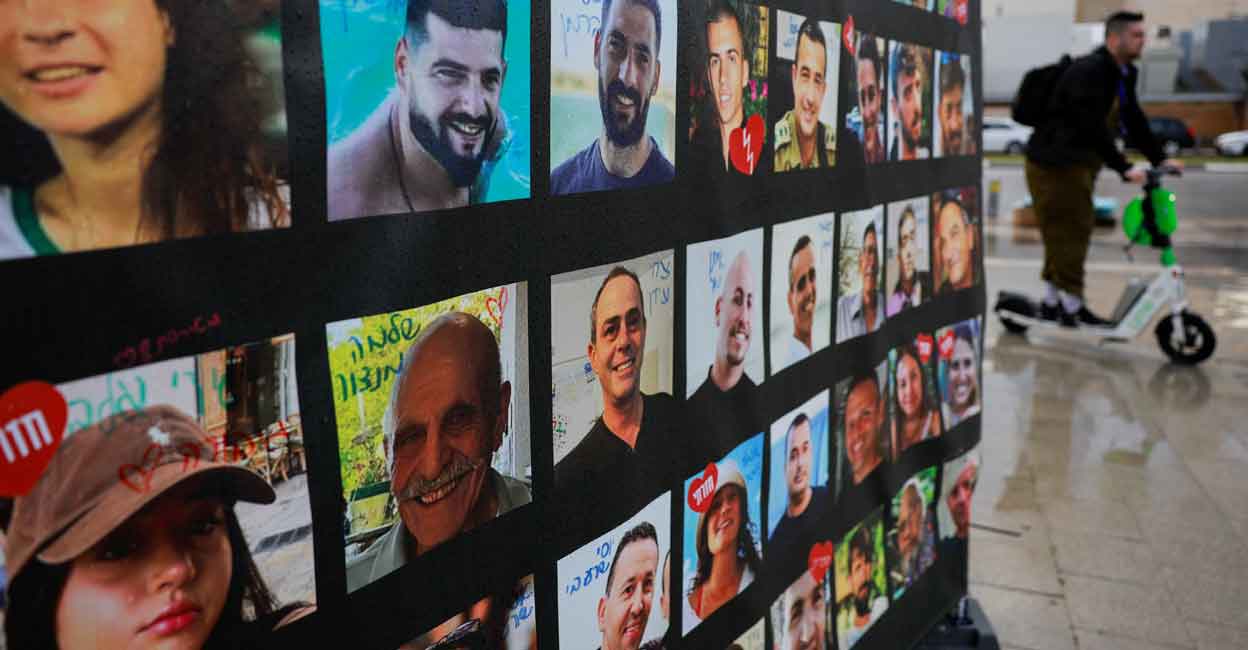 ISRAEL-PALESTINIANS-HOSTAGE-BODIES A man rides past a banner with pictures of hostages who were kidnapped during the deadly October 7, 2023 attack by Hamas. Photo: REUTERS/Ammar Awad