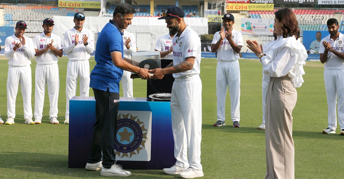 Virat Kohli gets his 100th Test cap from Rahul Dravid as Anushka Sharma looks on. Photo: Twitter/BCCI