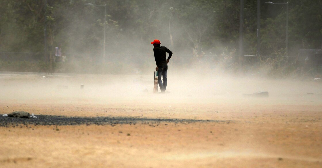 A boy waits for a brief dust storm to pass while playing cricket on a hot day in Ahmedabad. File photo: Reuters/Amit Dave