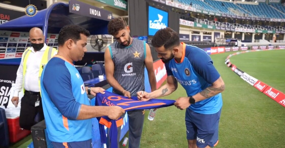 Virat Kohli signs the jersey. File photo: IANS
