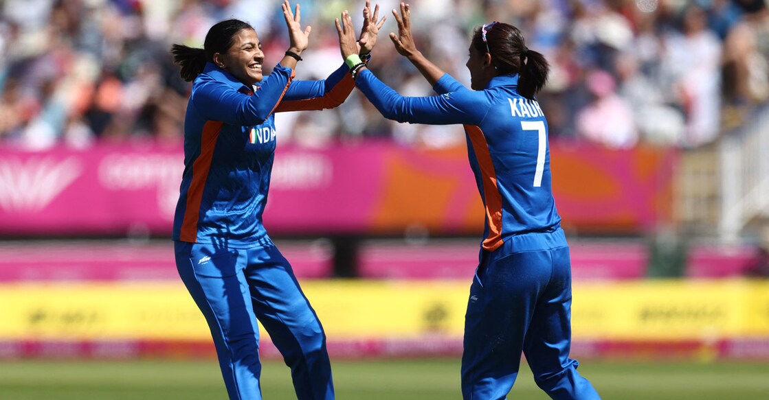 Sneh Rana and Harmanpreet Kaur celebrate the fall of an England wicket. Photo: AFP/Darren Staples