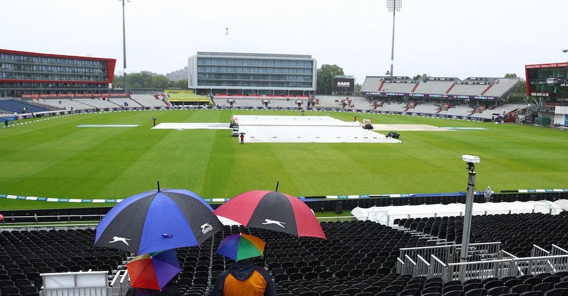 Spectators with umbrellas look on at the covers on the field. Photo: Action Images via Reuters/Lee Smith