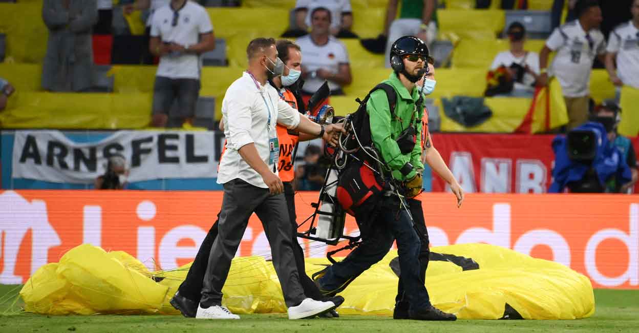 FBL-EURO-2020-2021-MATCH12-FRA-GER A paraglider, who flew inside the stadium sporting a message from environmental action group Greenpeace, is escorted by security after landing on the pitch. Photo: AFP