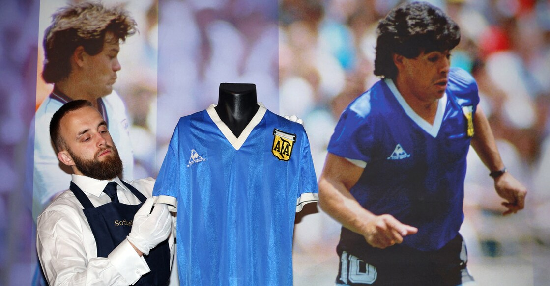 A technician adjusts the jersey worn by Diego Maradona during the 1986 World Cup quarterfinal during a photocall at Sotheby's auction house in London on April 20, 2022. File photo: AFP/ Adrian Dennis