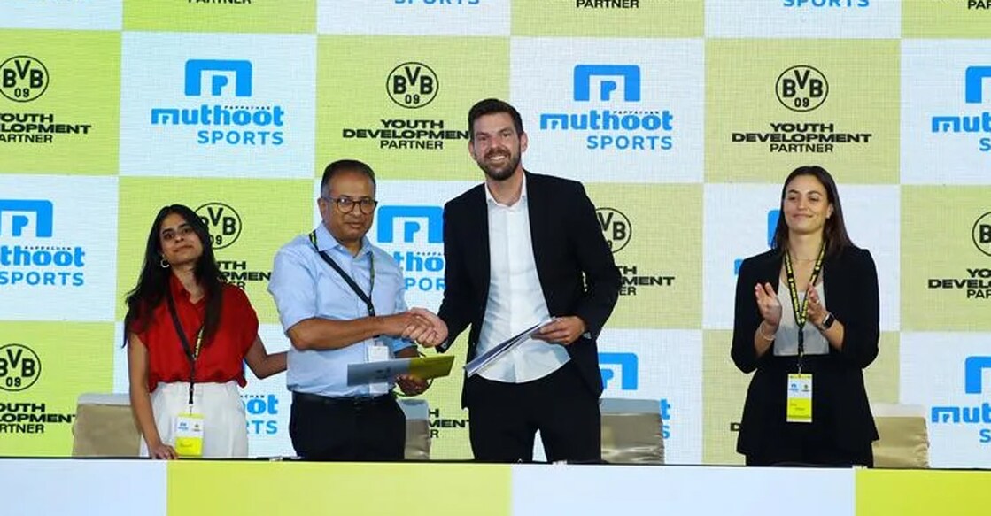 Thomas Muthoot, Director of Muthoot Pappachan Group and Chrisitan Diercks, Managing Director, BVB Evonik Football Academy shake hands after signing the MoU in the presence of Hannah Muthoot, Director, Muthoot Sports. Photo: Special arrangement