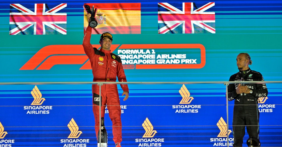 Ferrari's Carlos Sainz Jr. celebrates with the trophy on the podium after winning the Singapore Grand Prix alongside third placed Mercedes' Lewis Hamilton. Photo: Reuters/Caroline Chia