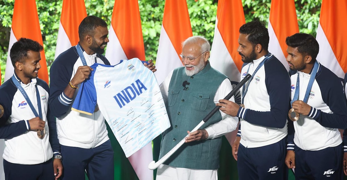 Souvenir P R Sreejesh presnts a jesery signed by the Indian hockey team to Narendra Modi. Photo: PTI