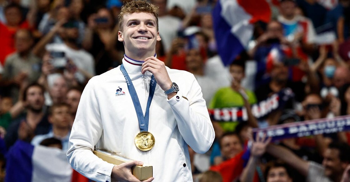 Leon Marchand celebrates on the podium after winning gold and setting a new Olympic record in 200m individual medley. Photo: Reuters/Clodagh Kilcoyne