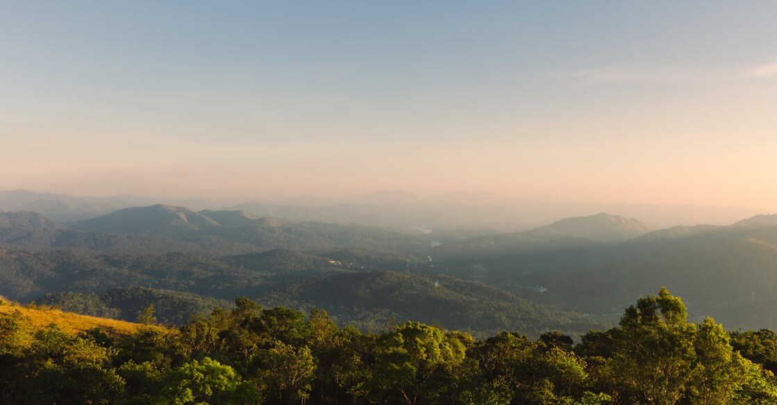 View across the cardomom hills in Thekkady under the misty sky during sunset. Photo: iStock/Danielrao