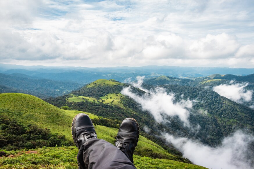 hiker resting at hilltop with breathtaking mountain layers in background image is showing the breathtaking beauty of nature at south india.