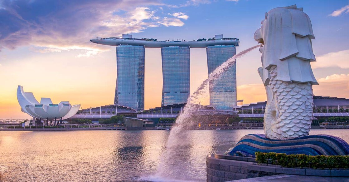 View of the sunrise from the Merlion Park in Singapore. The iconic Merlion statue and the Marina Bay Sands hotel are also seen. Photo: Shutterstock/Richie Chan