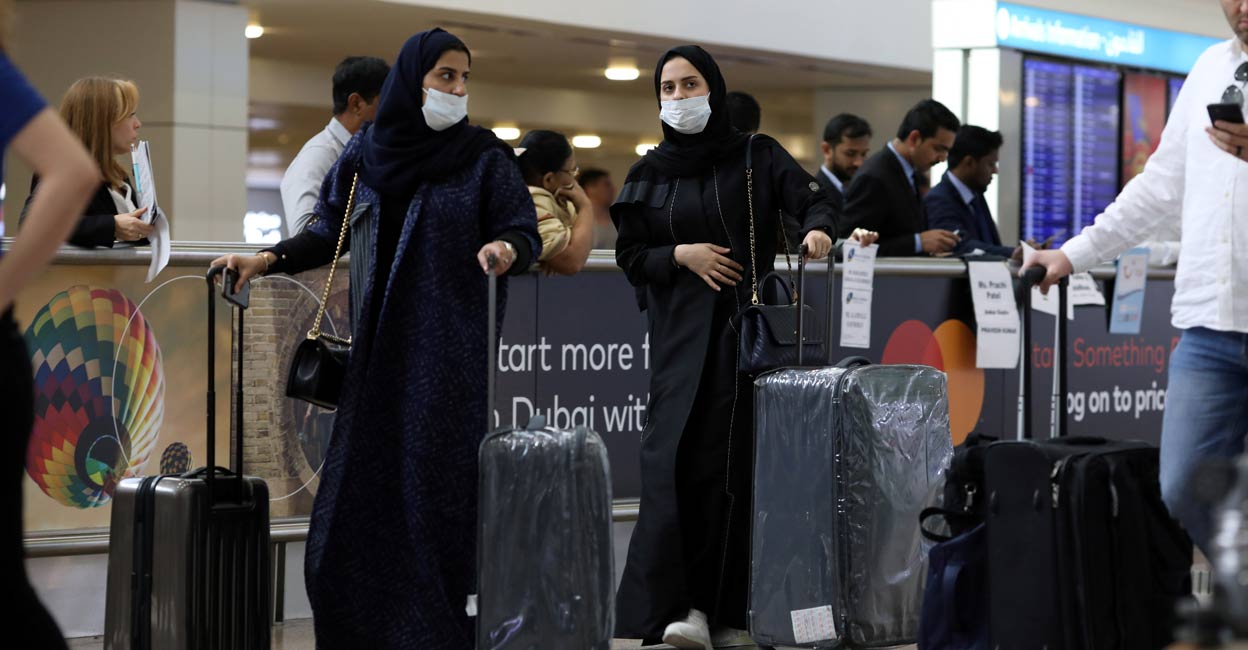 Travellers wear masks as they arrive at the Dubai International Airport