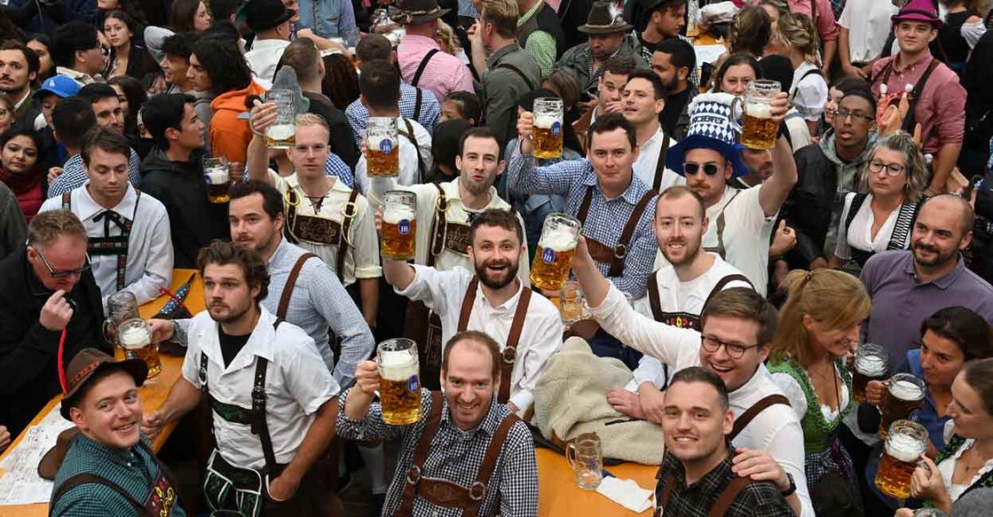 Visitors hold up their beer mugs as they celebrate during the opening of the Oktoberfest beer festival at the Theresienwiese fair grounds in Munich, southern Germany, on September 17, 2022.  The world renowned Beer festival is taking place from September 17 to October 3, 2022 without access restrictions, after the past two years' editions had been cancelled due to the coronavirus pandemic. Photo: Christof STACHE/AFP
