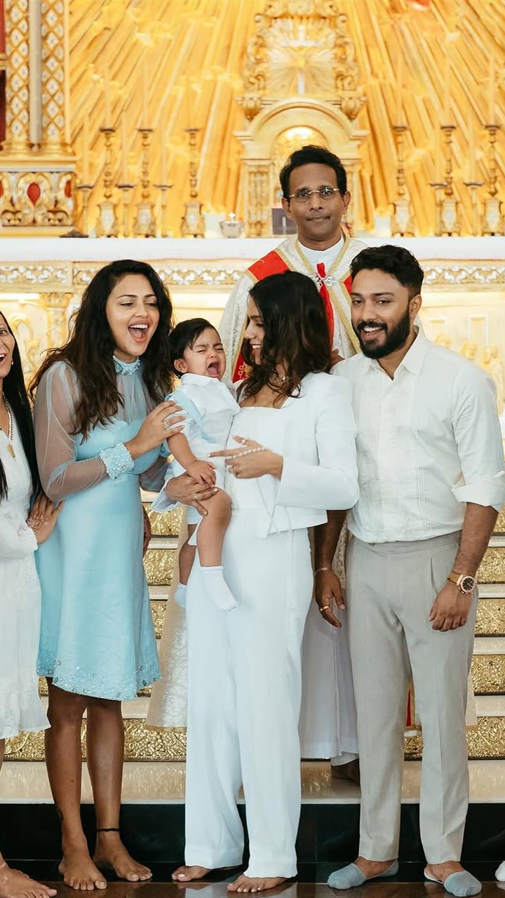 Amala wore an aqua blue mini frock, while Jagat wore a matching shirt with white shorts. Guests were dressed in white, creating a serene and elegant setting.